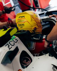 A close-up of a motorcycle featuring a yellow Monster Energy fuel tank, a helmet, and racing fairings with various sponsor logos.