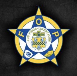 The badge of Fraternal Order of Police, Fort Pierce Lodge #71, featuring a blue and yellow star design with a city coat of arms in the center.