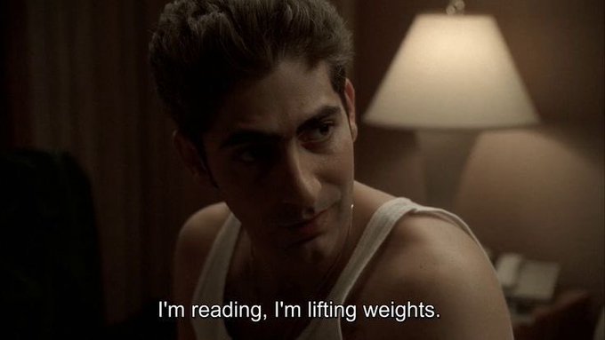 Man in a white tank top with the caption "I'm reading, I'm lifting weights."
