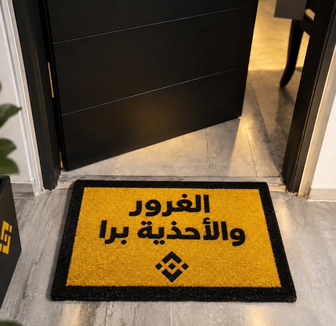 A doormat with Arabic text reading "الفورور والأحذية برا" (which translates to "Remove shoes outside") sits in front of a dark cabinet and doorway, reflecting the importance of keeping the interior space clean by removing footwear before entering. The mat humorously underscores the user's post about wiping themselves off before entering their personal "deals" or room.