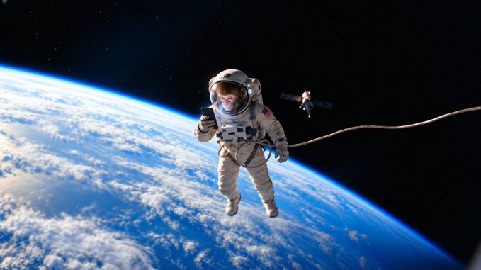 An astronaut in a white spacesuit floats tethered above Earth, with a satellite visible against the black expanse of space, illustrating the surreal "aping" joining it in, making space exploration feel easier than ever.