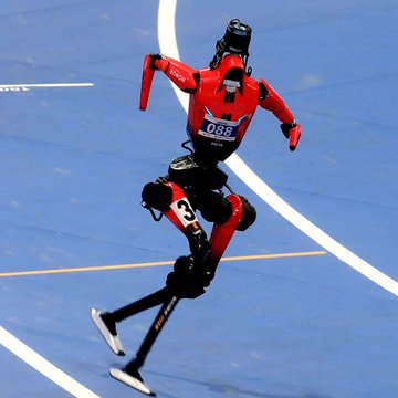 A figure in a red jacket, helmet, and roller skates performs a stunt on a blue track, wearing bib number '088' and leg padding with the number '80'.