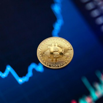 A physical Bitcoin token rests atop a digital price chart with blue trend lines, symbolizing the cryptocurrency's price movement. The image ties to the news that Bitcoin's one-month correlation with the S&P 500 has dropped toward zero, illustrating BTC's decoupling from traditional stock markets.