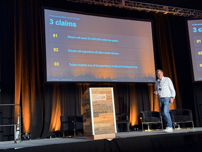 A speaker at the MWBTCSummit presents a keynote slide titled "3 claims," predicting that Bitcoin will reach $1,000,000 within ten years, outperform all other asset classes, and represent one of the best buying opportunities in its history. The stage features a wooden podium with the Bitcoin.US logo, supporting the post's bold claim that a Bitcoin price of $1 million in a decade is "fact not fiction."