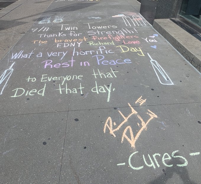 Chalk messages on a city sidewalk commemorating 9/11, reading '9/11 Twin Towers', 'Thanks for Strength! The bravest firefighters', 'FDNY Richard Love You', and 'What a very horrific Day Rest in Peace to Everyone that Died that day.'