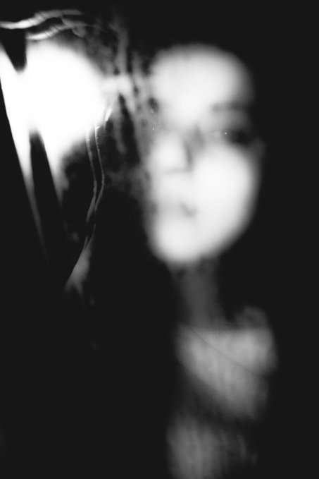 A haunting, blurred black-and-white double exposure showing the ghostly faces of a woman and another figure.