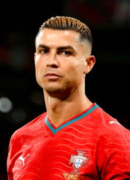 Close-up photograph of soccer player Cristiano Ronaldo wearing a red Portugal national team jersey with the federation logo visible.