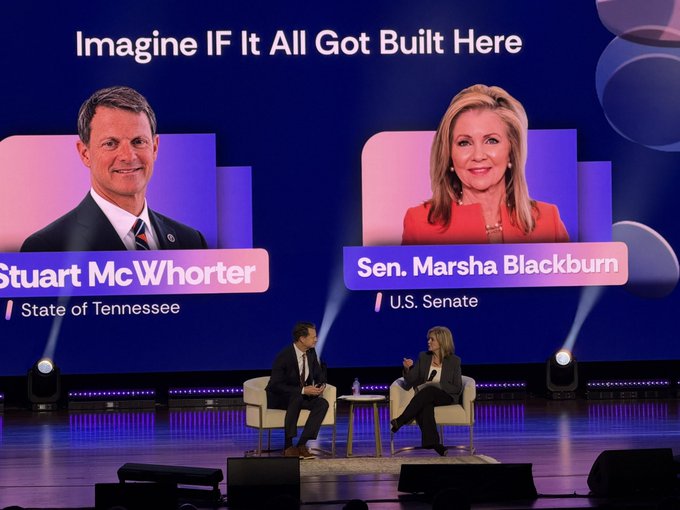 A panel discussion on a stage with two people seated in chairs; the large screen behind them reads "Imagine IF It All Got Built Here" and features headshots of "Stuart McWhorter, State of Tennessee" and "Sen. Marsha Blackburn, U.S. Senate."
