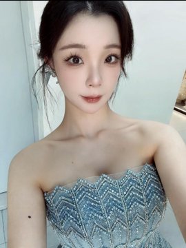 A woman with dramatic makeup and an embellished strapless dress shows off a new, glamorous look, aligning with her post about experimenting with different styles and feeling happy.