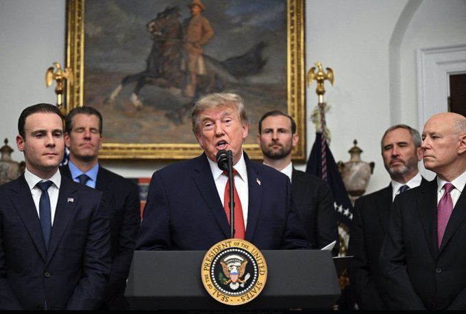President Trump speaks at a podium bearing the Seal of the President of the United States, flanked by several men. This image likely represents a significant event where the President's endorsement or presence could lend credibility to a subject, similar to how the post suggests XRP seeks widespread recognition.