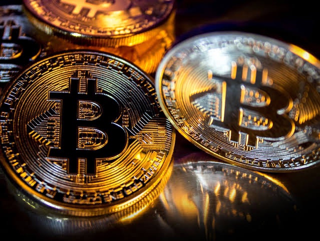 A close-up of golden Bitcoin cryptocurrency coins with the distinctive "₿" symbol visible on their surfaces.