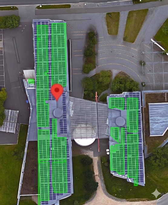 An aerial view of a building with its rooftop covered in green solar panels, marked with a red Google Maps location pin.