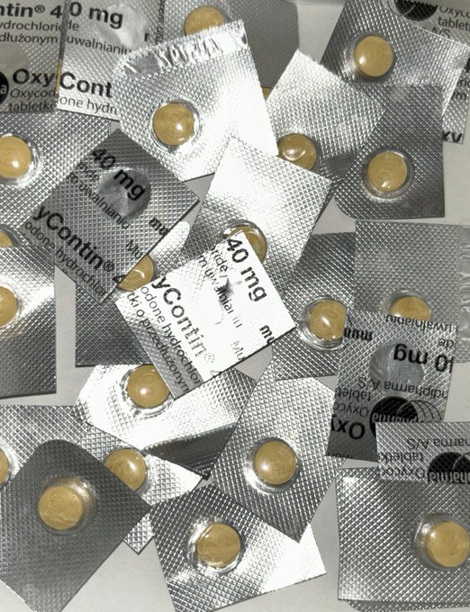 A pile of OxyContin 40 mg blister packs containing yellow oxycodone hydrochloride tablets, with the brand name 'OxyContin' and 'oxycodone hydrochloride' text visible on the silver packaging.