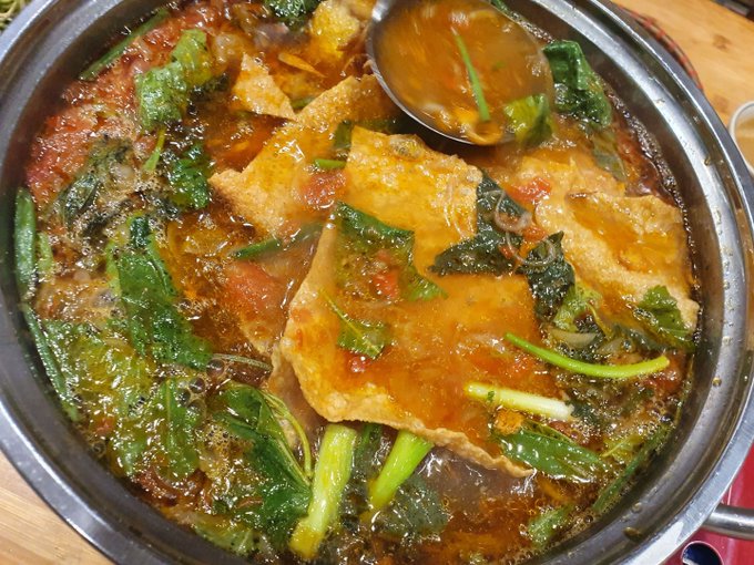 A bubbling hot pot filled with fried tofu and leafy greens in a rich tomato broth, paired with a "Good Friday Dinner" message to signal stepping away from the markets for a well-earned meal.