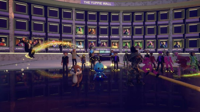 A screenshot from a 3D virtual world or game showing various cartoonish avatars gathered in a grand hall with a large wall of screens labeled "THE YUPPIE WALL," featuring a flying character leaving a sparkly trail.