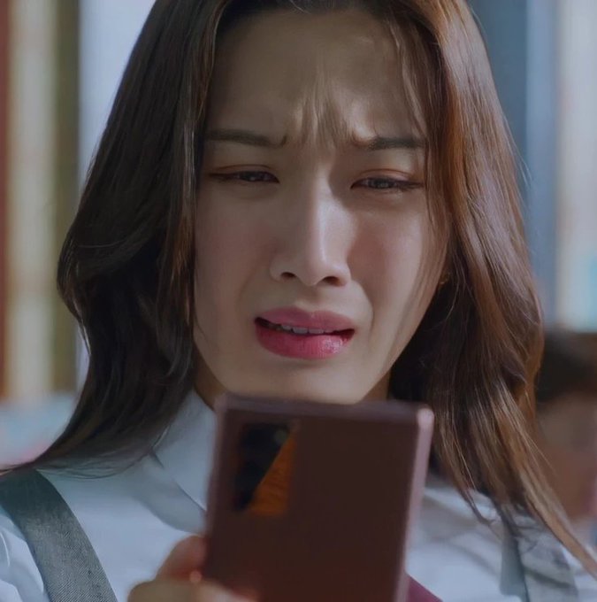 A young woman with long brown hair is shown crying while looking down at a smartphone in her hand, appearing deeply distressed by something on the screen. The emotional reaction visually reinforces the post's message about being overwhelmed by too many token launches on the Robinhood platform.