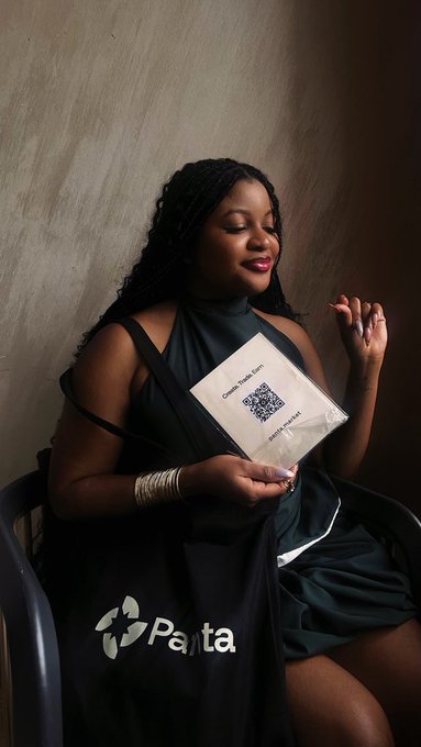 A woman with long braided hair sits smiling while holding a Panta bounty envelope featuring a QR code, alongside a "Panta" branded tote bag. The image celebrates her first Earn win with Superteam Nigeria, made possible through partnerships with @PantaHQ and @Nectar_finance.
