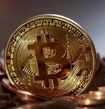 A close-up of a gold Bitcoin coin resting on a pile of coins, symbolizing the record $730.9 million in net inflows to spot Bitcoin ETFs, with BlackRock's $IBIT leading the surge at $454 million.