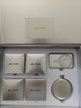 An open MOBX branded gift box containing five small white packages and a circular metal container with a white cap.