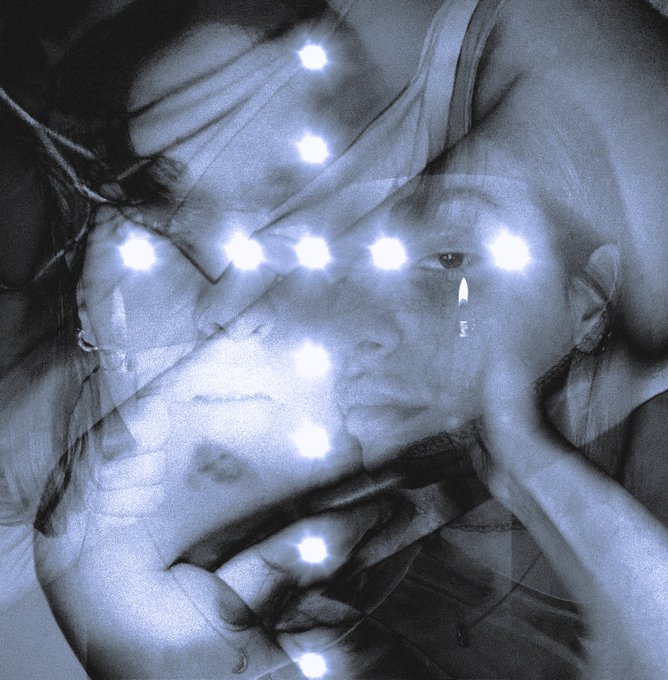 An artistic, monochromatic double-exposure portrait of a person resting their head on their hand, overlaid with a triangular arrangement of bright lights.