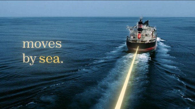 A large cargo ship sailing on the ocean with a yellow laser-like beam trailing behind it, overlaid with yellow text reading 'moves by sea.'
