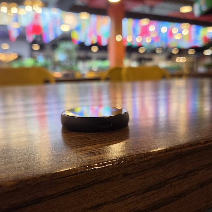 The image shows a black cell phone sitting on top of a wooden table, with a blurred background that includes chairs and tables. The text in the image suggests that there are times when just CT announcements or exchange listings moved markets are over, which implies that the focus should be on creating real products and delivering them to real users rather than solely relying on CT announcements or exchange lists. This idea is reflected in the image's title "Times when just CT announcements or exchange listings moved markets are over".