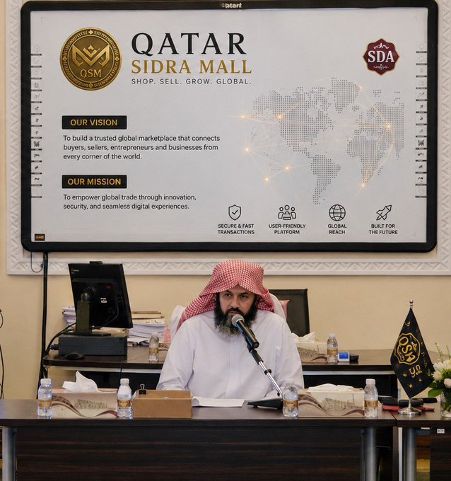 A man in traditional Gulf attire sits before a screen displaying "Qatar Sidra Mall" and its vision: "To build a trusted global marketplace that connects buyers, sellers, entrepreneurs and businesses from every corner of the world." The setting reflects the post's announcement of a new global commerce platform, with the presenter appearing to share details about the upcoming launch.