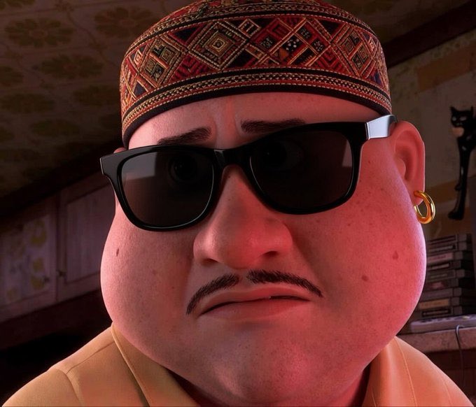 A close-up of a stylized 3D-animated character with a mustache, sunglasses, gold earring, and a patterned traditional cap, set against an interior background.