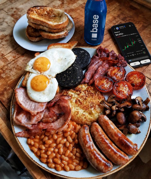 A hearty full English breakfast featuring fried eggs, bacon, sausages, baked beans, black pudding, ham, hash browns, grilled tomatoes, and sautéed mushrooms is plated alongside toast and a blue "base" branded water bottle, with a smartphone displaying a Baseapp portfolio balance of "$0.013"; the post playfully frames the protein-rich meal as part of a crypto investor's morning routine with Base app.