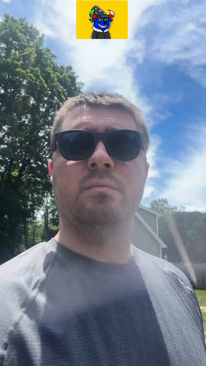 The image features a man wearing sunglasses, standing outdoors with his face partially obscured by them. The background includes trees and houses, suggesting that he might be outside during the day or at dusk when the sun sets behind the buildings. The photo also contains text elements related to an NFT platform, which could possibly be about the sale of digital artworks or other creative projects on the internet.