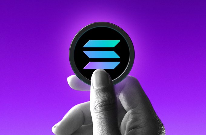 A stylized image showing a grayscale hand holding up a glowing, circular Solana (SOL) cryptocurrency logo with its characteristic three-bar symbol against a vibrant purple background.