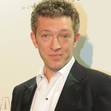 A man with short curly hair in a dark suit and white shirt poses at what appears to be a media event, with partial text "at CH..." visible in the background. The image accompanies a post featuring Dominic Williams making a bullish price prediction about the $ICP cryptocurrency token.