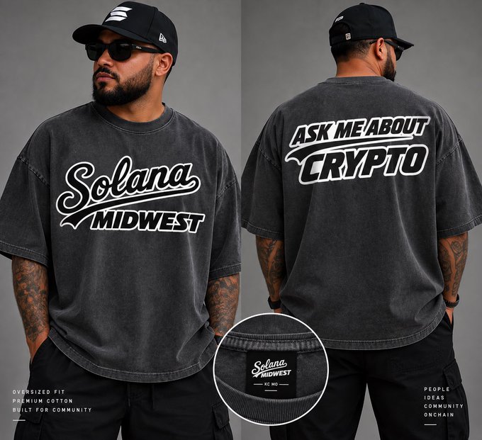 A promotional image showing the front and back of an oversized, washed black t-shirt reading 'Solana MIDWEST' on the front and 'ASK ME ABOUT CRYPTO' on the back, with labels 'OVERSIZED FIT,' 'PREMIUM COTTON,' and 'KC, MO.'