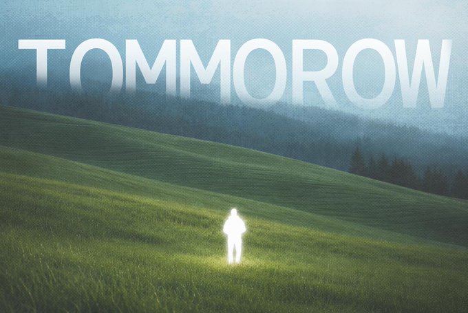 A luminous figure stands alone in a vast green field with misty hills in the background, beneath the word "TOMMOROW" displayed in large letters across the sky.
