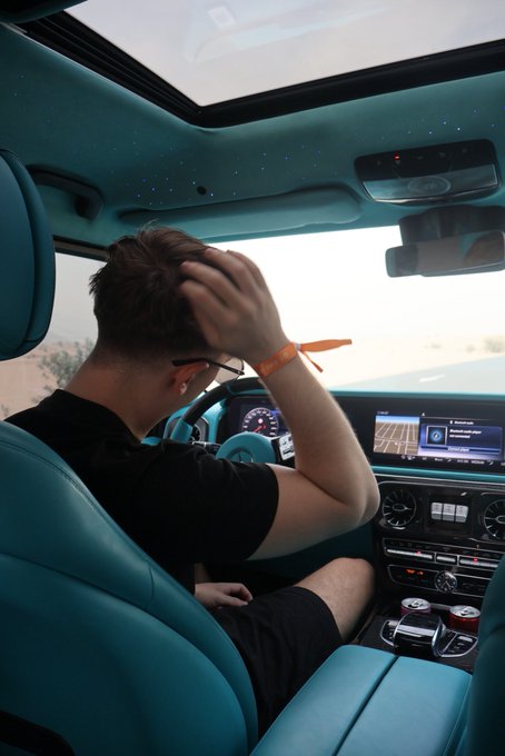 A young man with sunglasses sits in the driver's seat of a luxurious car featuring a striking teal interior and starlight headliner, adjusting his hair in a moment of casual confidence. The image perfectly embodies the "GM if you GM" vibe, showcasing high-end style and an aspirational lifestyle.

(Note: No readable text, numbers, or tickers are visible in the image.)