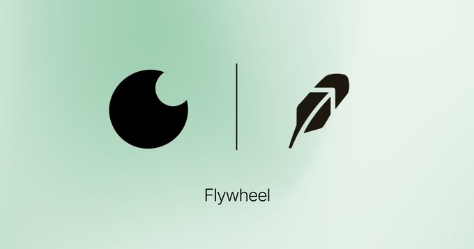A graphic showing a black logo with a circle and a feather icon separated by a line, with the text 'Flywheel' underneath.