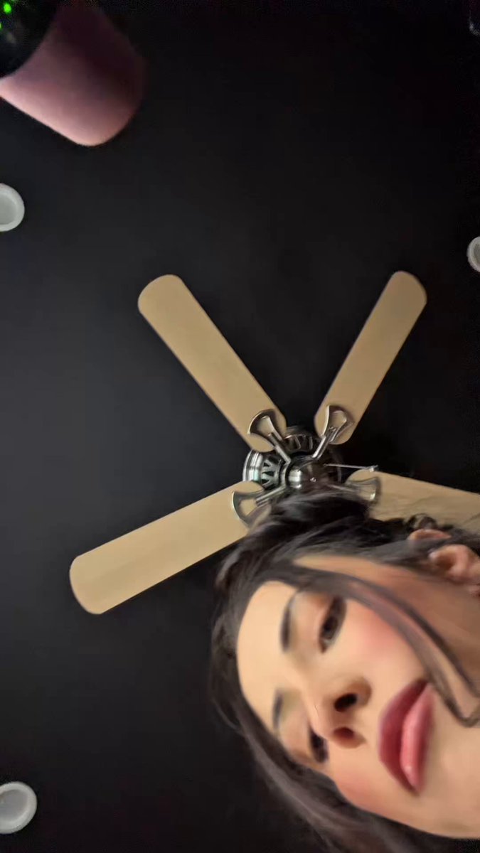 The image features a woman with long hair wearing lipstick, looking up at a ceiling fan that has four blades. The photo appears to be taken from an unusual angle or perspective, giving it a unique and interesting look. The caption provided seems unrelated to the main subject of the image and is not directly related to the content displayed in the image.
