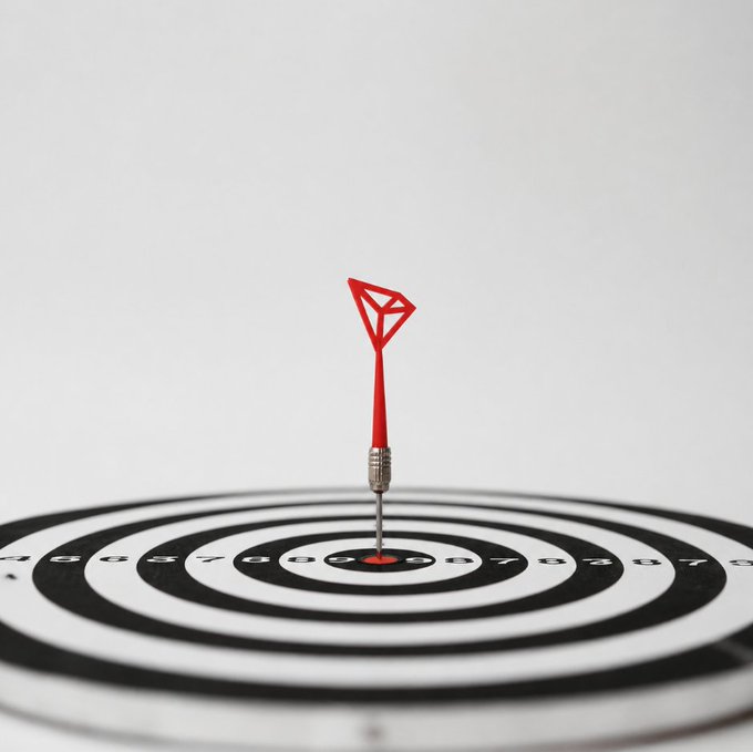 A close-up of a red dart hitting the bullseye of a black and white target with numbered scoring rings.