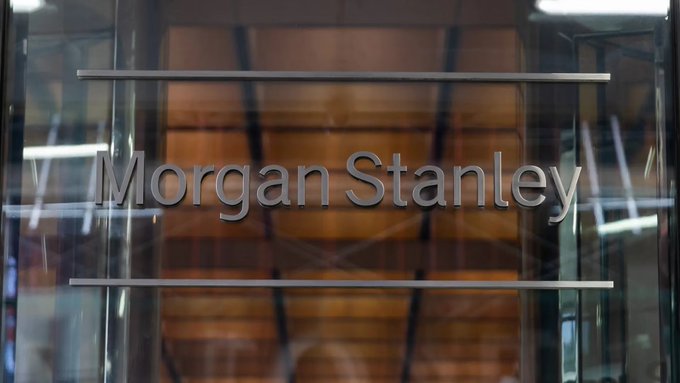 The image shows the "Morgan Stanley" name displayed in metallic lettering on a glass building facade, reflecting warm interior lighting. This branding directly represents the financial institution referenced in the post as it explores digital assets and blockchain-based innovations like stablecoins and tokenization.