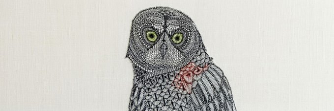 The image shows an intricately embroidered owl with detailed black beadwork or stitching on light fabric, featuring striking yellow-green eyes and a decorative pink bow around its neck. It aligns with the accompanying post as a custom banner design featuring an owl—the visual symbol of the Solana token ticker "OWL."