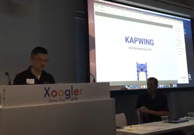 A man presenting at 'Xoogler Demo Day 2018' with a 'KAPWING' slide showing 'hello@kapwing.com' projected behind him.