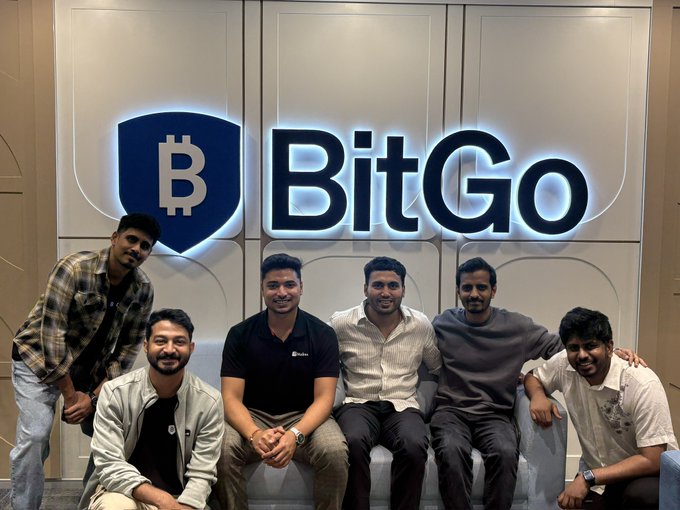 Six men pose for a group photo in front of an illuminated "BitGo" logo featuring a Bitcoin shield.
