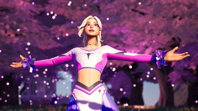 A blonde cheerleader in a pink and white uniform strikes an outstretched pose beneath cherry blossom trees, with a giant "GM" logo in the background—visually reinforcing the "good morning" greeting.