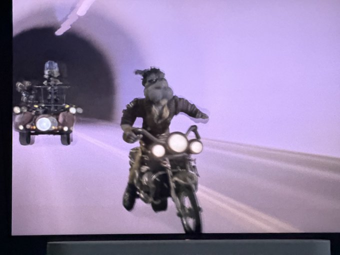 A scene from an animated movie showing two characters riding motorcycles through a tunnel, with the lead character driving a bike with dual headlights.