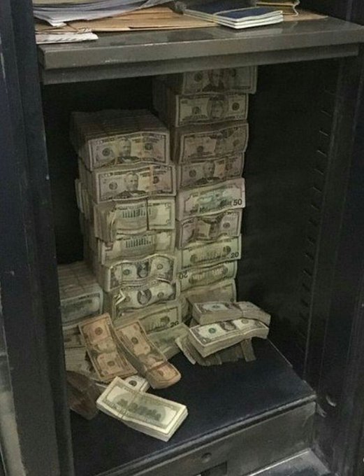 An open metal safe is packed with numerous banded stacks of US dollar bills in various denominations.