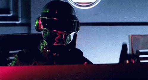 ildj.com/v/Disco-Gangster is shown wearing a black leather jacket and helmet, seated at a desk with a computer monitor and keyboard.