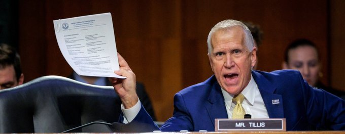 Senator Thom Tillis, identified by the "MR. TILLIS" nameplate, raises a document while speaking with an intense expression during a Senate hearing, illustrating his concerns about the CLARITY Act's passage. His forceful gesture emphasizes his message that the legislation's chances have dropped sharply due to upcoming elections.