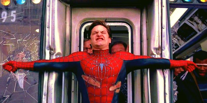 A man in a Spider-Man costume is being forced through a subway car door while several people push from behind, appearing to be from the movie Spider-Man 2.