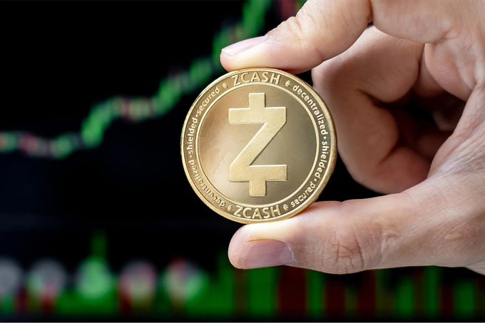 In this image, someone's hand is holding up a coin labeled "Zcash" against an economic chart with zeros representing the currency and dollar symbols for $. The caption below the coin reads "5 Billion.. Gone in a Day Zcash (Zcash) cryptocurrency plunged by more than 50% in a single day.. With nearly 5 billion dollars evaporating from its market value, which is estimated at 9 billion dollars." The image emphasizes the decline of Bitcoin's worth and highlights how much money has been lost as a result.