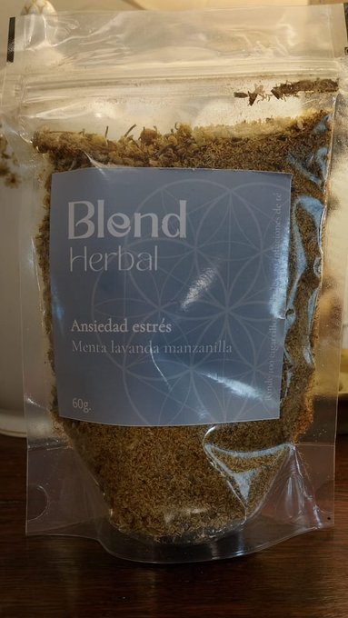 A plastic package of 'Blend Herbal' tea (60g) labeled 'Ansiedad estrés' with mint, lavender, and chamomile (menta lavanda manzanilla), resting on a wooden surface.